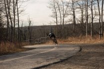 Rückansicht Biker fährt Mountainbike auf Straße — Stockfoto