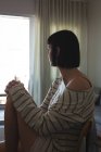 Беспокойная женщина сидит на диване в гостиной дома — стоковое фото