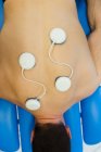Man lying on chest with electrode pads on back in clinic — Stock Photo