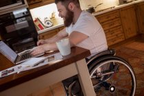 Homem com deficiência observando ao usar laptop em casa — Fotografia de Stock