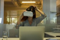 Ejecutiva con auriculares de realidad virtual en la oficina - foto de stock
