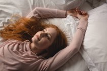 Mujer reflexiva relajarse en la cama en el dormitorio en casa - foto de stock