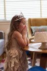Удивлённая девушка смотрит на свой праздничный торт дома — стоковое фото
