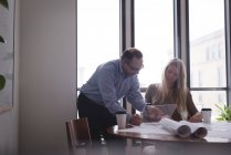 Compañeros de negocios discutiendo sobre tableta digital de vidrio en la oficina - foto de stock