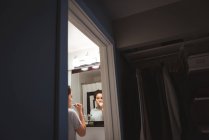 Молодая женщина, стоящая перед зеркалом, чистит зубы в ванной комнате дома — стоковое фото