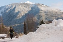 Человек катается на велосипеде по снежной улице зимой . — стоковое фото