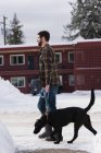 Mann läuft im Winter mit Hund auf Gehweg. — Stockfoto