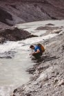 Homme randonneur se laver les mains dans la rivière par une journée ensoleillée — Photo de stock