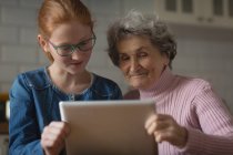 Großmutter und Enkelin nutzen digitales Tablet in der heimischen Küche — Stockfoto