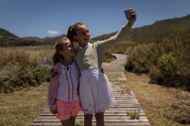Happy siblings taking selfie with mobile phone on jetty — Stock Photo