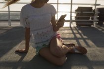 Partie basse de la femme utilisant un téléphone portable sur un bateau de croisière — Photo de stock