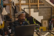 Внимательный человек с ноутбуком в мастерской — стоковое фото