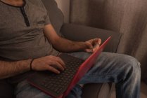 Чоловік використовує ноутбук на дивані у вітальні вдома . — стокове фото