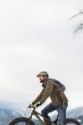 Чоловік їде на велосипеді в сніжному гірському пейзажі взимку . — стокове фото