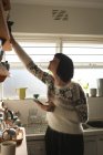 Жінка використовує мобільний телефон під час роботи на кухні вдома — стокове фото