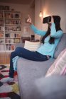 Mulher usando fones de ouvido de realidade virtual na sala de estar em casa — Fotografia de Stock