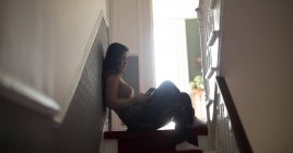 Frau benutzt Handy im Treppenhaus zu Hause — Stockfoto