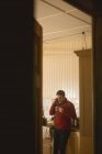 Чоловік розмовляє по бездротовому телефону, маючи каву вдома — стокове фото