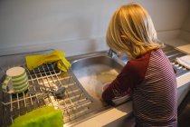 Vista trasera del niño trabajando en la cocina en casa - foto de stock