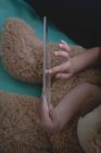 Vista recortada de chica con oso de peluche usando tableta digital de vidrio en el dormitorio - foto de stock