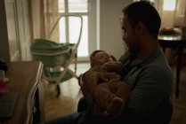 Père tenant son bébé dans le salon à la maison — Photo de stock