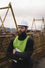 Thoughtful dock worker standing with arms crossed in shipyard — Stock Photo