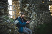 Male hiker using mobile phone in old ruins at countryside — Stock Photo