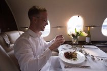 Бізнесмен фотографує їжу з мобільним телефоном у приватному літаку — стокове фото