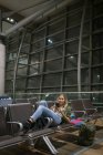 Frau benutzte Handy im Wartebereich am Flughafen — Stockfoto