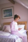 Жінка використовує цифровий планшет на ліжку в спальні вдома — стокове фото