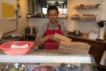 Personale maschile imballaggio cibo in sacchetto di carta in caffetteria — Foto stock