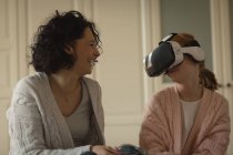 Мати посміхається, коли дочка використовує гарнітуру віртуальної реальності вдома — стокове фото