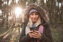 Junge Frau benutzt Handy im Wald. — Stockfoto