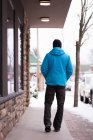 Homem andando com as mãos nos bolsos na calçada durante o inverno . — Fotografia de Stock