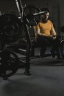 Инвалид с помощью мобильного телефона на скамейке прессы в тренажерном зале — стоковое фото