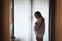 Schwangere blickt auf ihren Bauch und hält ihn fest — Stockfoto