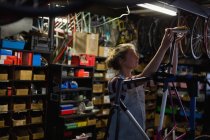 Jovem mecânica feminina fixação de bicicleta na oficina — Fotografia de Stock