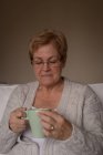 Старша жінка має каву у вітальні вдома — стокове фото