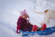 Cute girl playing in saucer sled during winter — Stock Photo