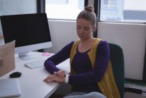 Blonde weibliche Führungskraft mit Smartwatch im Büro — Stockfoto