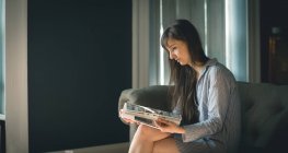 Frau liest Magazin im Wohnzimmer zu Hause — Stockfoto