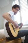 Людина, грав на гітарі в спальні в домашніх умовах — стокове фото