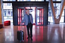 Бизнесмен входит в отель с багажом — стоковое фото