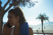 Frau mit Handtuch telefoniert an Tropenküste — Stockfoto