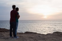 Романтична пара обіймається на пляжі на заході сонця — стокове фото
