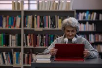 Active senior woman using laptop in library — Stock Photo