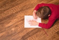 Мальчик рисует на бумаге дома — стоковое фото