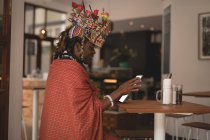 Масаї людина в традиційному одязі, використовуючи цифровий планшетний в ресторані — стокове фото
