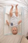 Портрет милого малыша, лежащего на кровати и смотрящего в камеру дома — стоковое фото