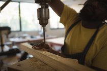 Nahaufnahme des Tischlers beim Bohren von Holzplanken mit Maschine in der Werkstatt — Stockfoto